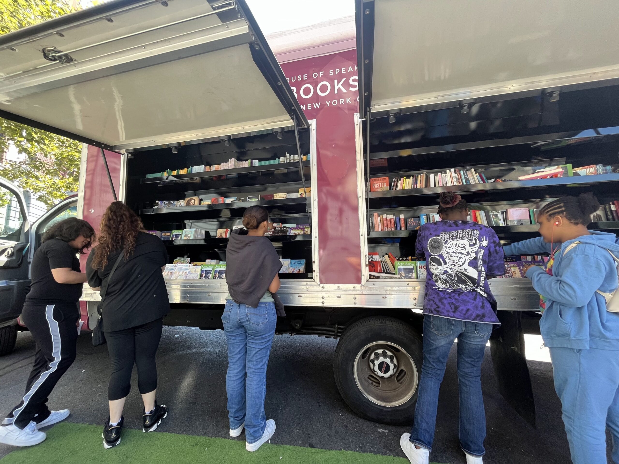 A crowd of young children gathers around House of SpeakEasy's Bookmobile