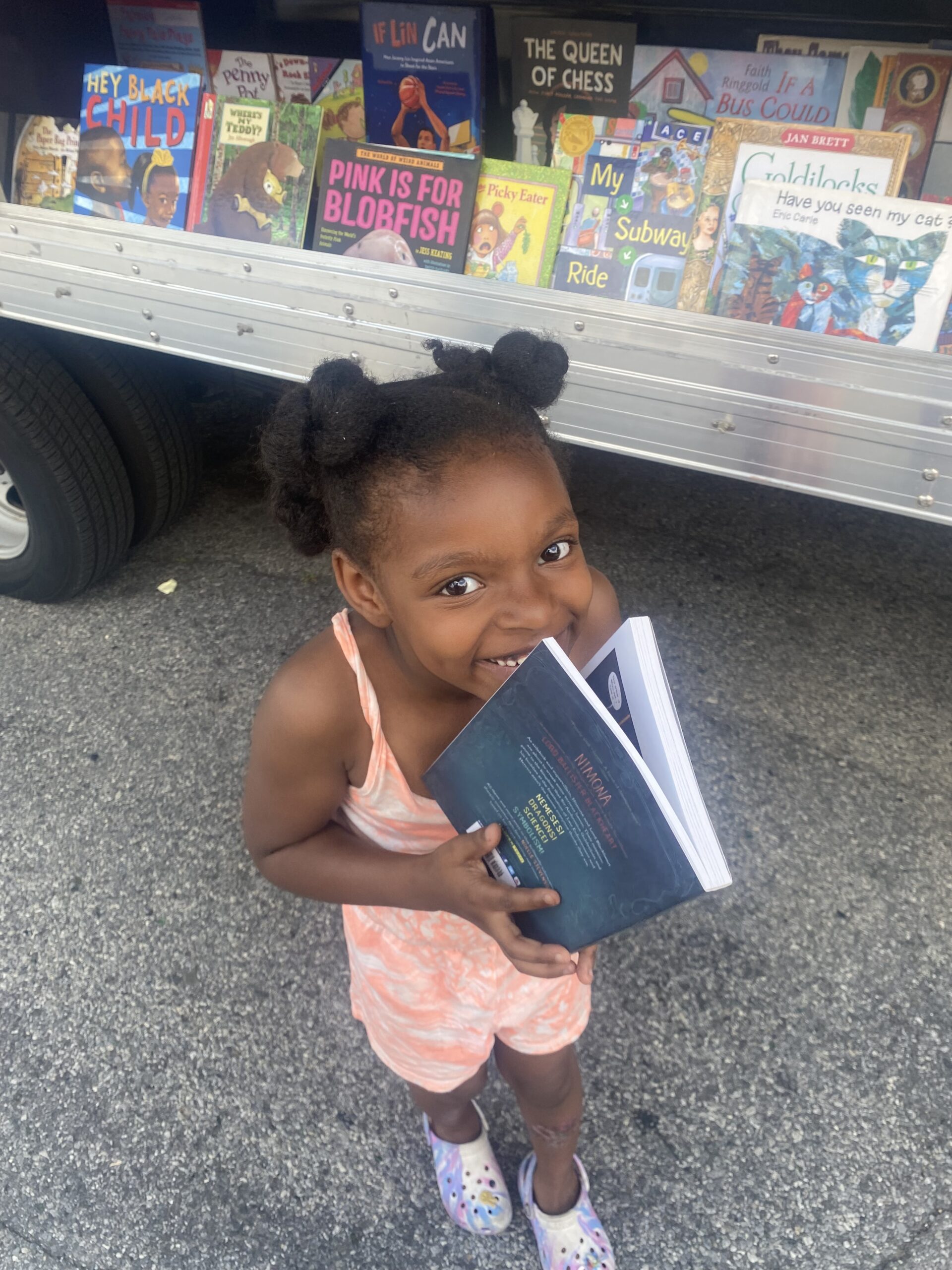 A crowd of young children gathers around House of SpeakEasy's Bookmobile